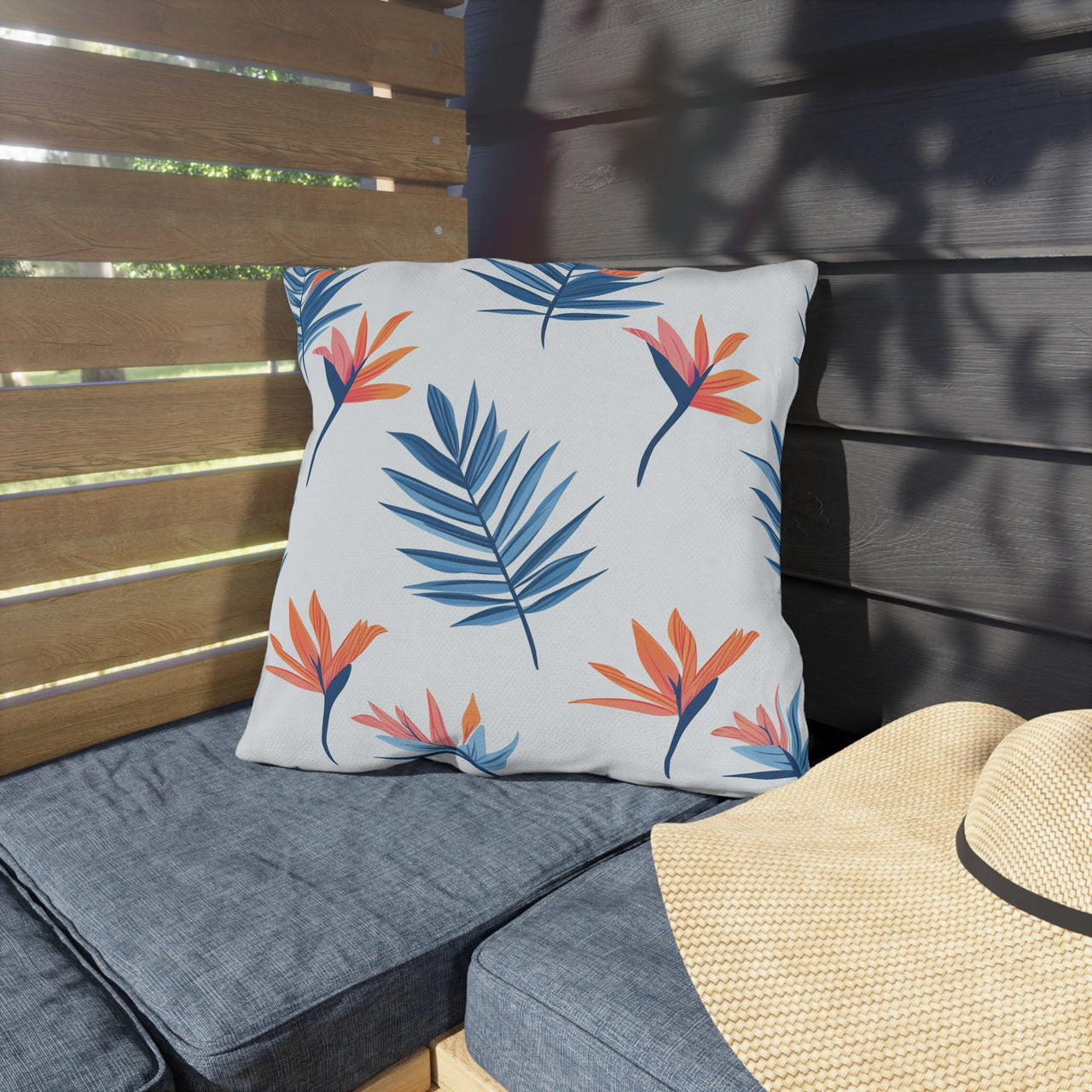 Floral-patterned pillow on a wooden bench with a straw hat nearby
