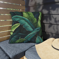 Thumbnail for Tropical leaf patterned pillow on a gray cushion with a straw hat on a wooden bench.