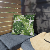 Thumbnail for Green leaf-patterned pillow on a gray cushion with a straw hat on a wooden bench.